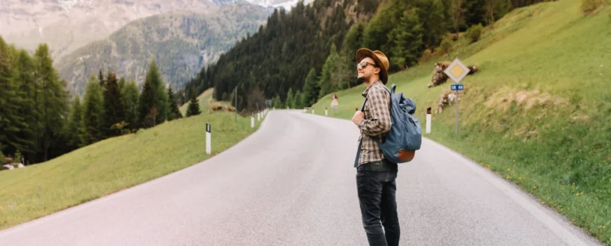 young-man-trendy-hat-standing-middle-highway-looking-away-enjoying-fresh-air-near-italian-alps